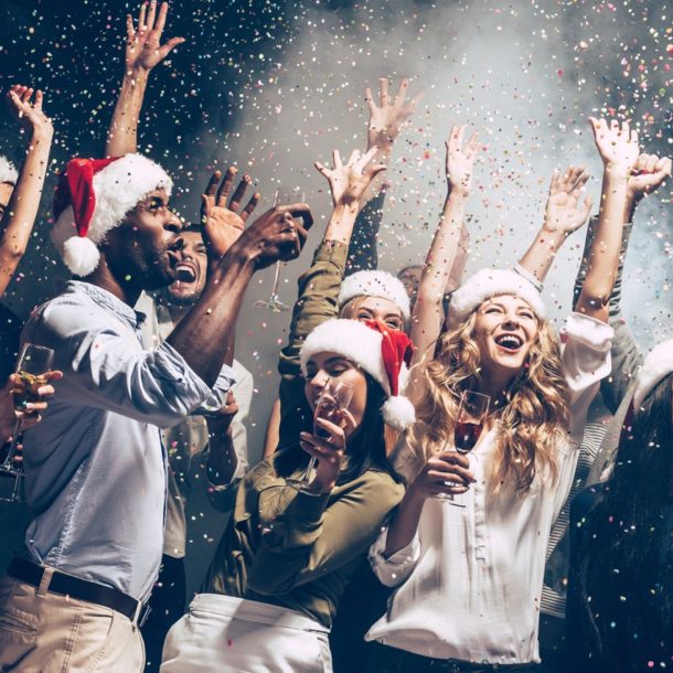 People dancing with santa hats in front of smoke and a black background