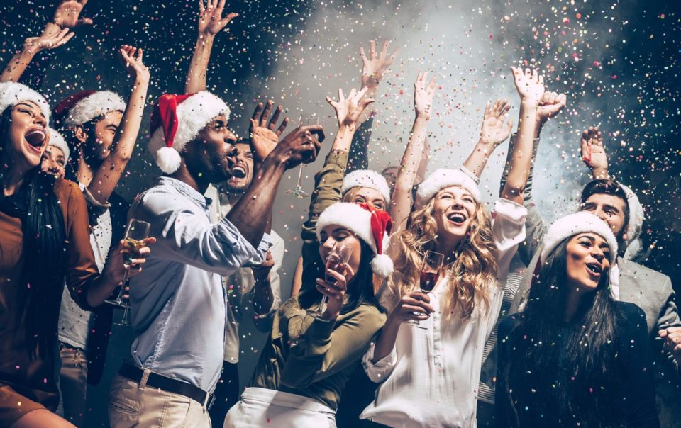 People dancing with santa hats in front of smoke and a black background