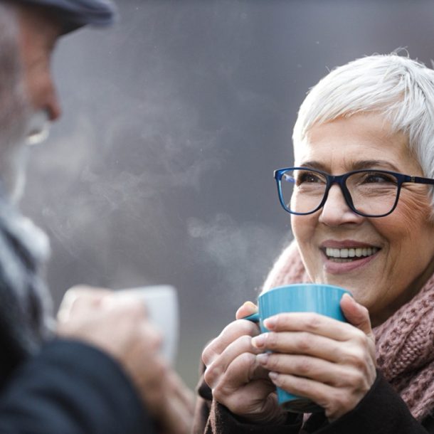 Elderley couple enjoying a hot drink outside in the cold as they warm into winter.